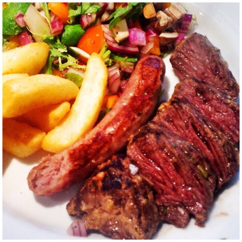 The final result, sliced served with chips, sausage and salad